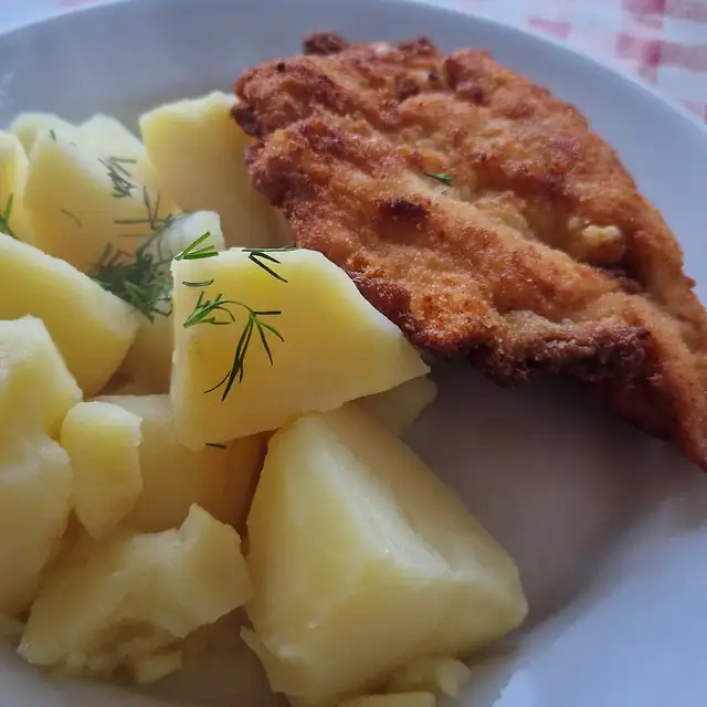 Kotlet panierowany z ziemniakami posypanymi koperkiem